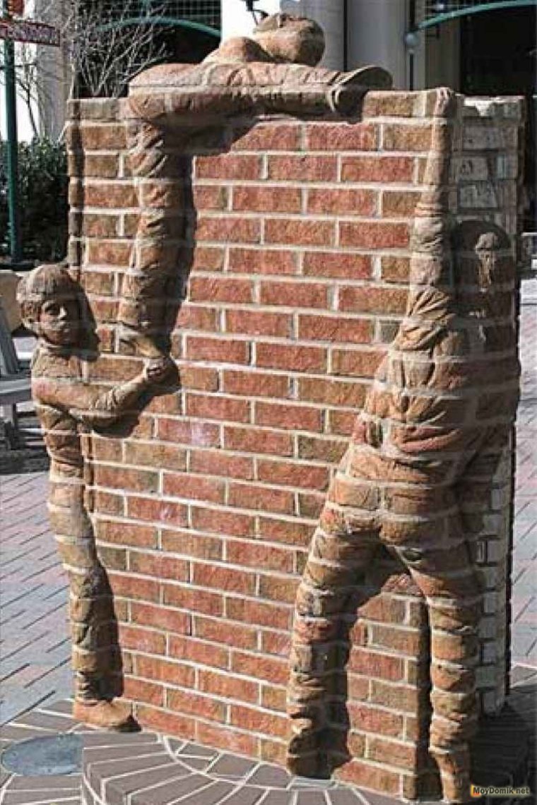Скульптура у кирпичной стены
