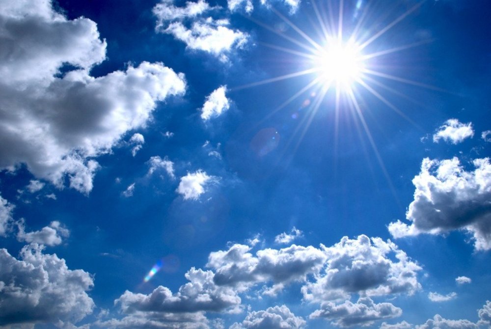Фото солнца с лучами среди облаков на голубом небе