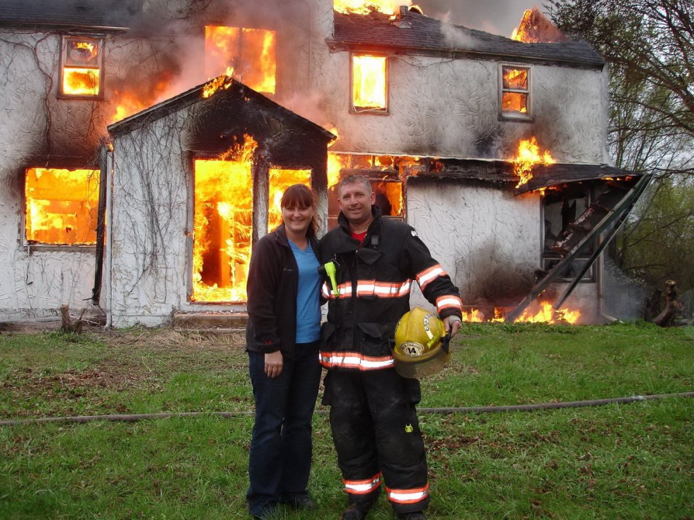 Пожарные на фоне горящего дома