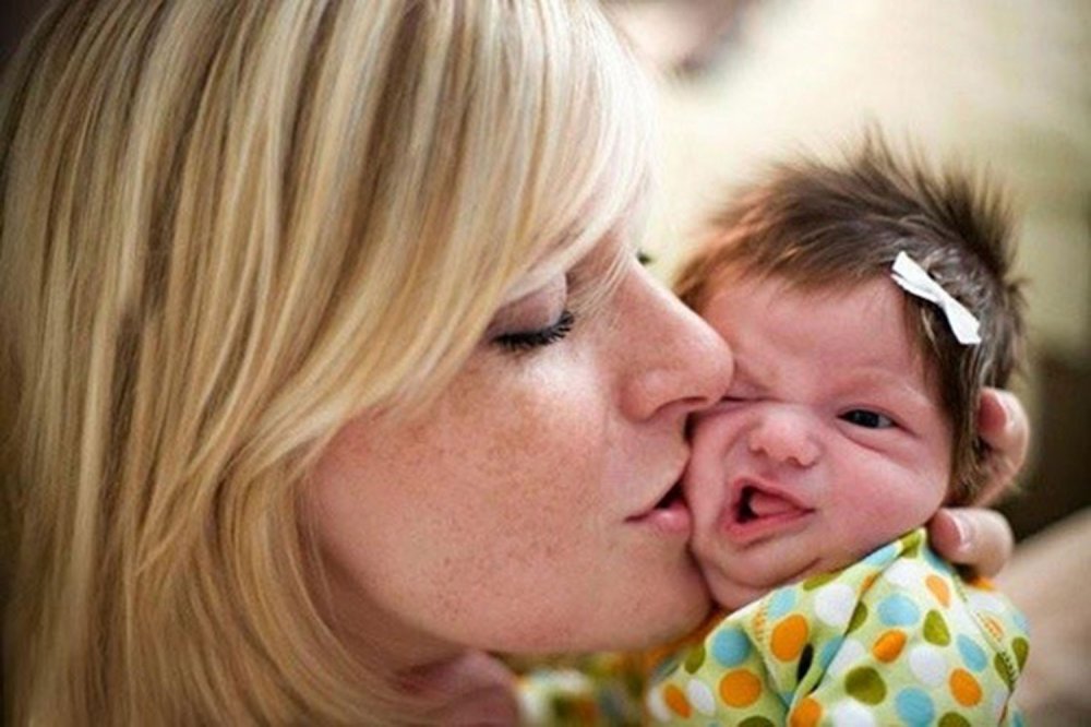 Родители целуют ребенка в щеки