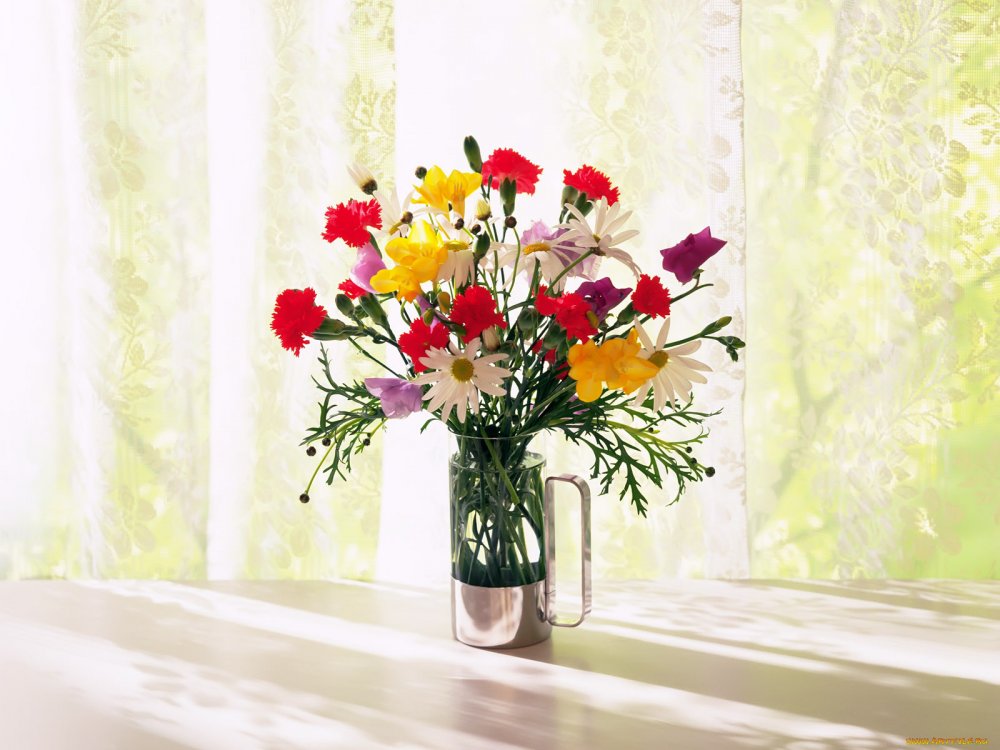 Яркие цветы в вазе на подоконнике